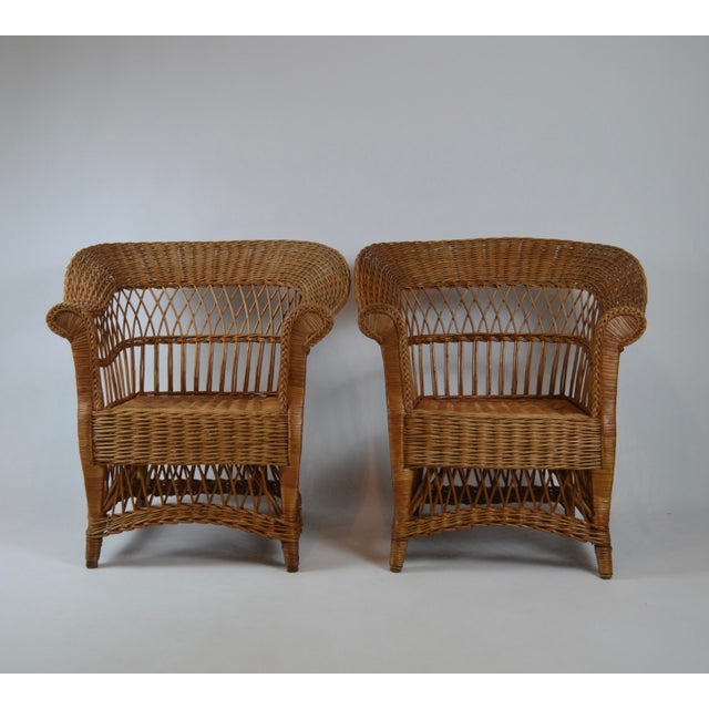 Elegant pair of early 20th-century wicker armchairs, dating from circa 1900–1920. The chairs feature an unusually...