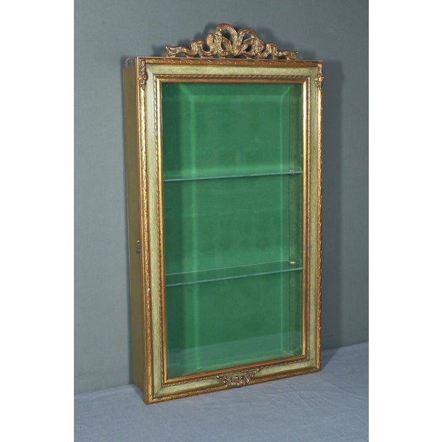 This gilded wood wall display case, dating from the mid-20th century, embodies classic refinement with its meticulously...