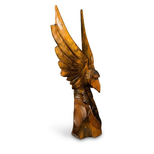 A dramatic and finely detailed vintage hand-carved wooden sculpture depicting an eagle perched atop a tree stump with...