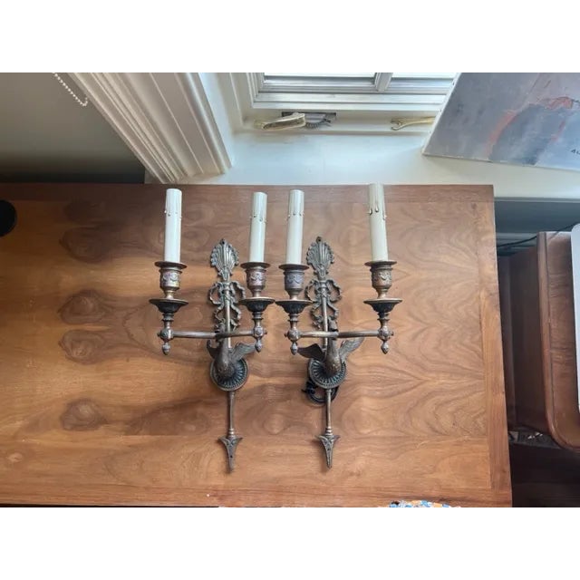A pair antique of ornate two arm French Empire sconces from the early 20th century featuring a swan and bow motif. Rewired.