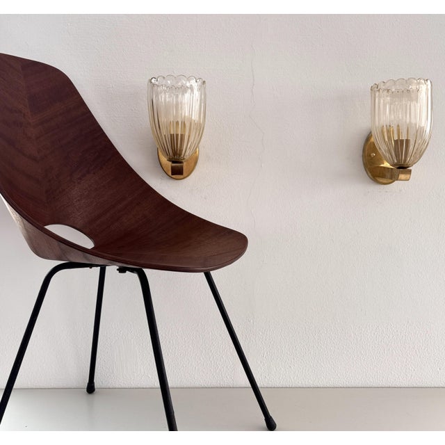 Beautiful set of two brass wall lamps made of strong brass base and light amber colored murano glasses with real golden...