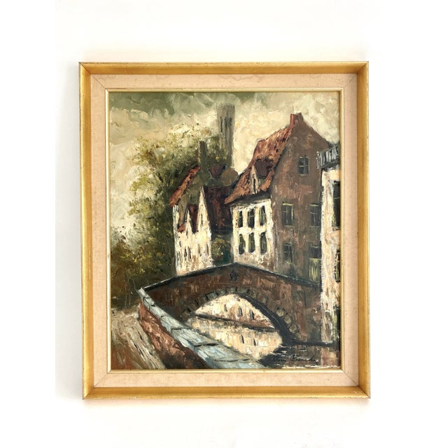 Sourced in Belgium, this bold landscape featuring a bridge in Bruges is displayed in its original gold leaf frame. Age...