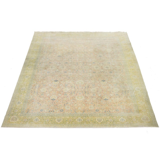 Experience the exquisite charm of this antique Tabriz hand-knotted oversized wool rug. Its captivating tan and peach-hued...