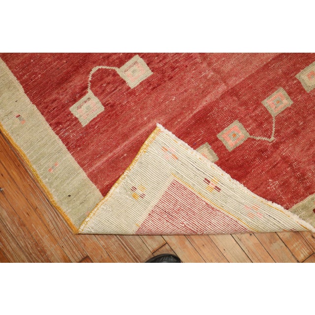 An abstract midcentury Turkish Anatolian rug with a brick red field with accents in green and pink. Size: 4'6” x 7'2”...