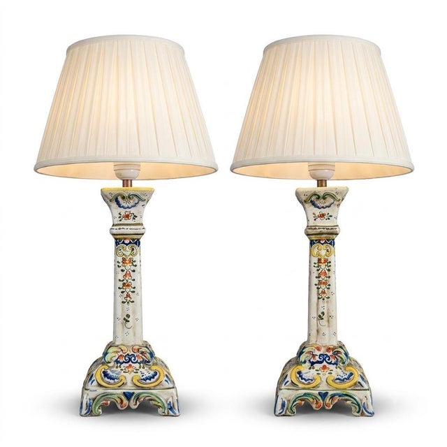 Pair of French faience table lamps dating to circa 1900–1910, with hand-painted Rouen-style floral and scroll decoration....