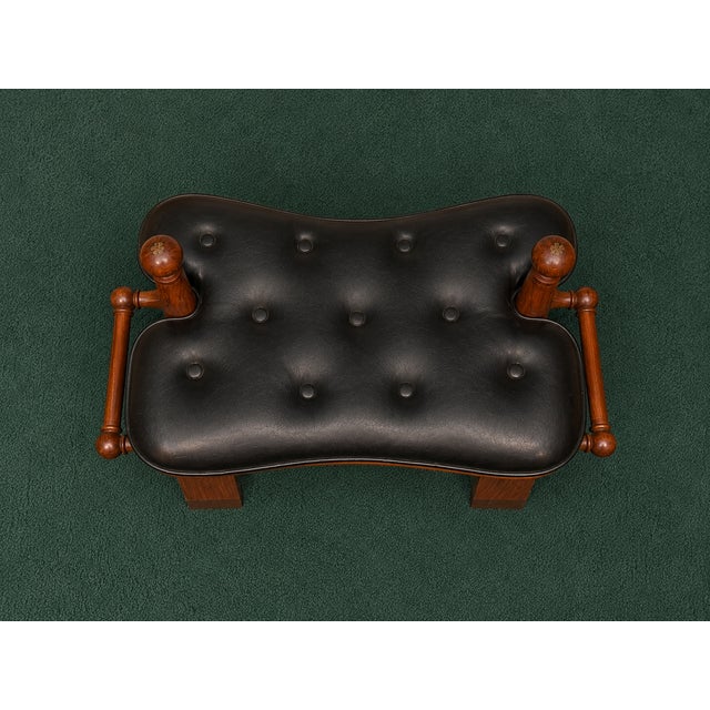 Vintage camel saddle stool featuring a tufted black leather cushion