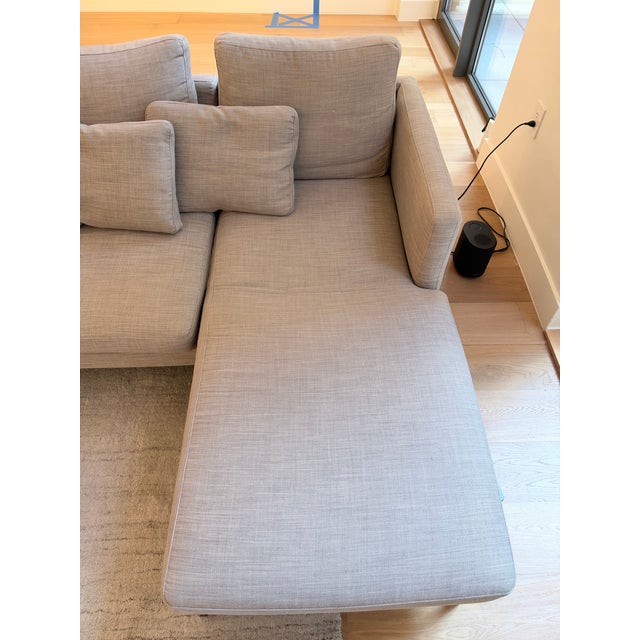 Sleek, modern BoConcept sectional with a light gray textured fabric, slim arms, and brushed steel legs. Comes with a...