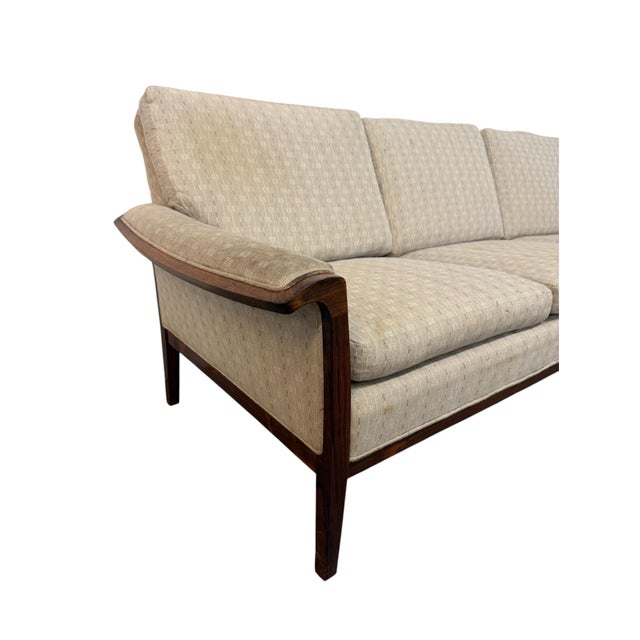A striking Mid-Century Danish Modern rosewood upholstered sofa, circa 1960s, featuring beautifully sculpted arms, tapered...