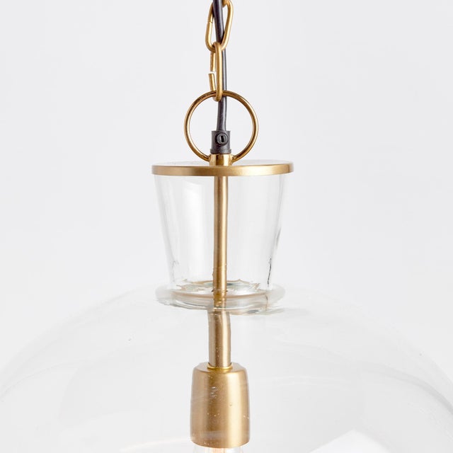 A classic mix of warm brass and seeded glass in grand scale, this pendant is a traditional fixture. Over an island, in an...