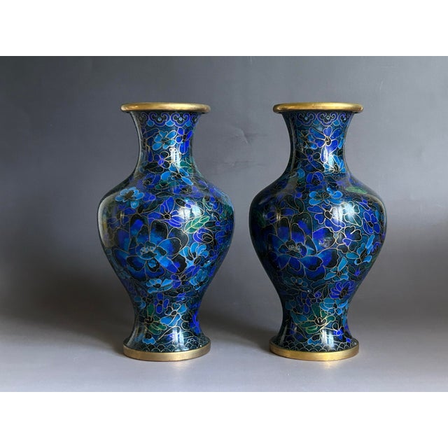 This elegant pair of mid-20th-century Chinese cloisonné vases features traditional floral motifs rendered in vivid cobalt...