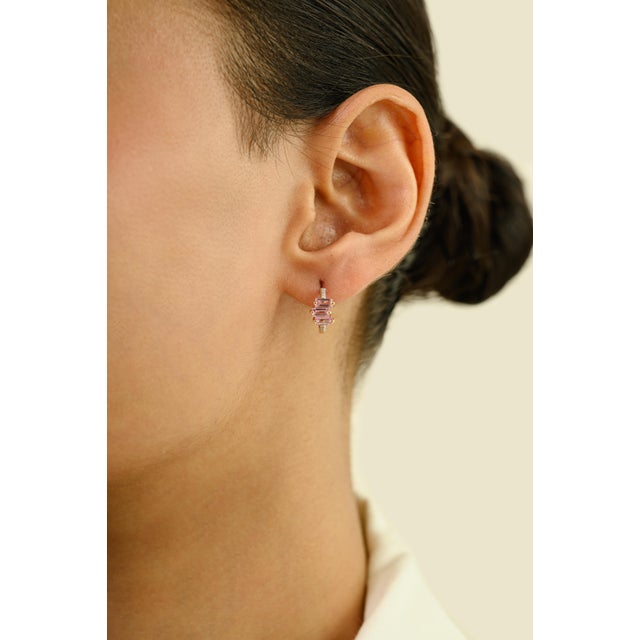 These huggie hoop earrings feature 6 baguette cut pink sapphire totaling 0.87 carats, set in rich 14k yellow gold. Each...