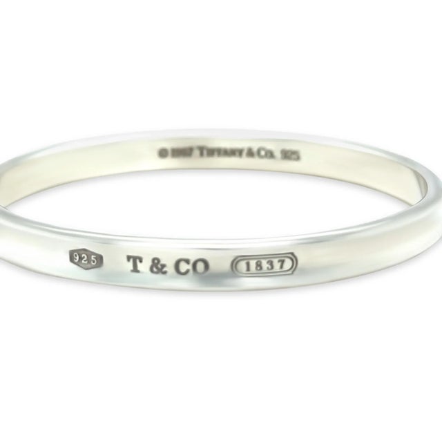 This sleek and polished Tiffany & Co. 1837 narrow bracelet is crafted in sterling silver, featuring the elegant curved...