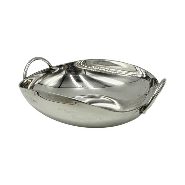 A polished silver-plated trinket dish by Christian Dior, made in Italy and executed in an elegant rounded form with...