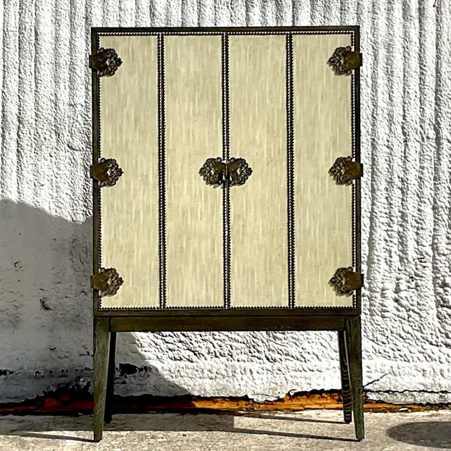 A spectacular vintage Boho dry bar cabinet. The iconic Arteriors 60 inch Chelsey cabinet. Beautiful wrapped linen doors...