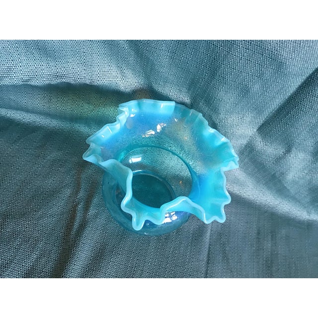 Description: Vintage aqua-blue art glass rose bowl featuring a wide hand-ruffled/crimped rim with milky white opalescent...