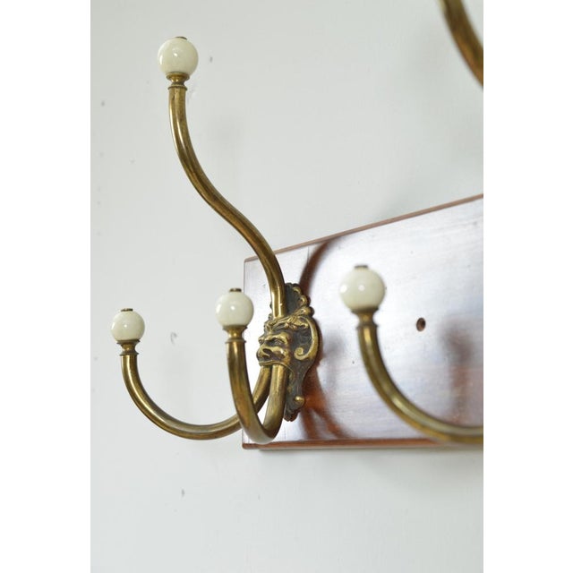 A rare set of four large antique brass and ceramic hat and coat hooks depicting a mythical “green man” or satyr-like...