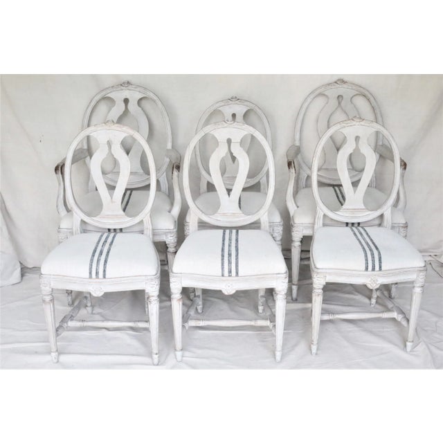 A set of six mid 19th century Swedish dining chairs in the classic oval back Gustavian style with bold carved rose crest...