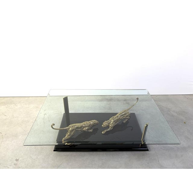 Fantastic coffee table featuring two detailed bronze Jaguar sculptures in fighting position mounted on a black pinao...