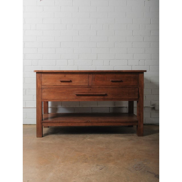A substantial solid wood work table defined by its clean lines, honest joinery, and warm, matte patina. The surface...
