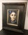 This oil on panel work captures a woman adorned for the Day of the Dead, her face painted with traditional skull motifs...