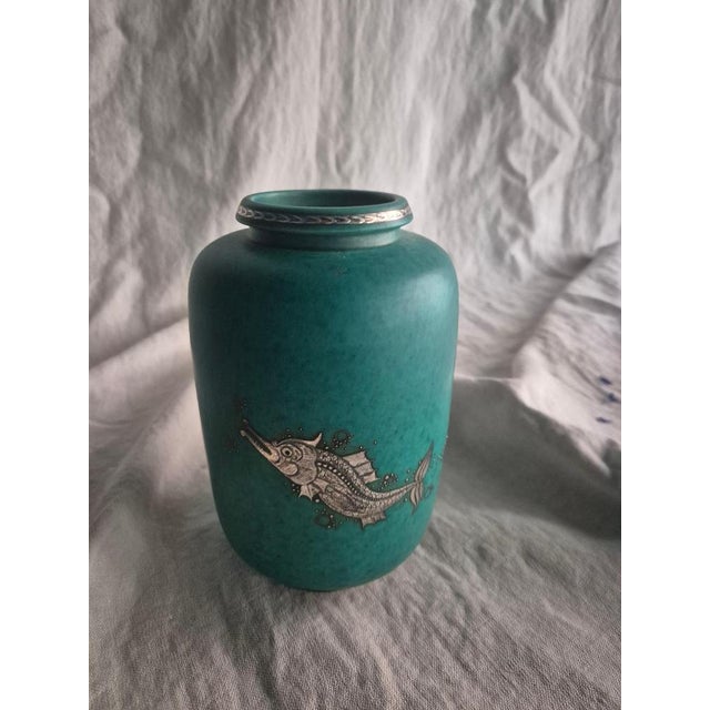 A swedish modern classic, stoneware vase in signature green glaze with decor of a mythical fish at play, and stripe at the...