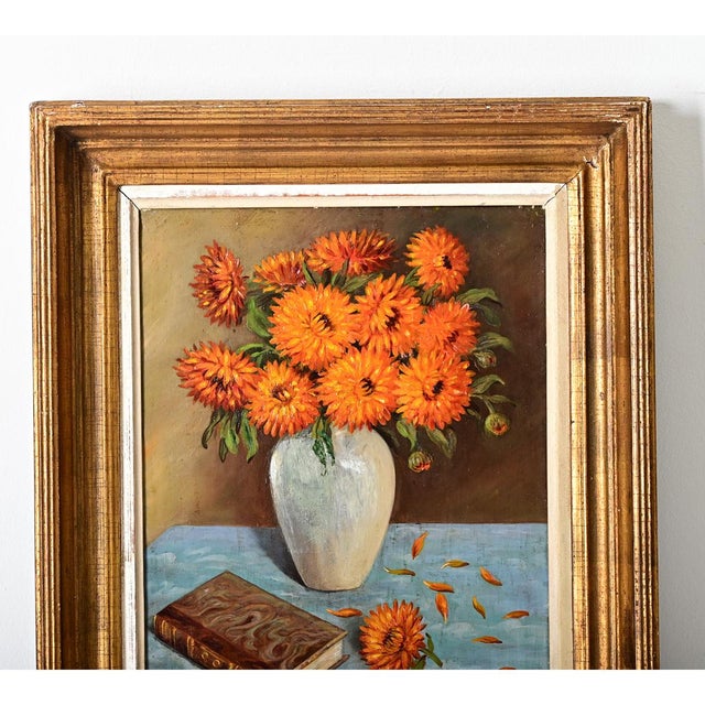 French vintage framed oil on canvas still-life painting of a vase of symbolic orange mums. In the foreground one can...