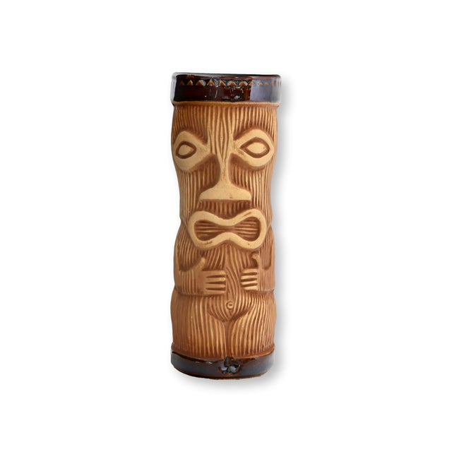 Mid 20th century set of eight ceramic tiki tumblers featuring classic carved mask decoration and warm earth-toned glaze....