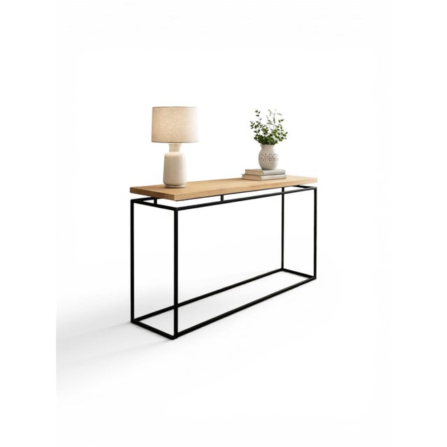 A striking modern console table featuring a thick natural wood top paired with a sleek black metal frame. Designed in a...