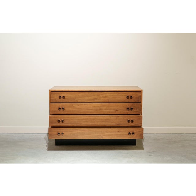 Small chest of drawers with four drawers on a black lacquered plinth made of walnut wood with double circular handles.