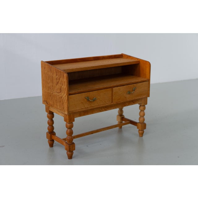 Danish Brutalist Oak Bedside Table, 1970s. Small two drawer commode in Henning Kjærnulf style on a base with bobbin legs....