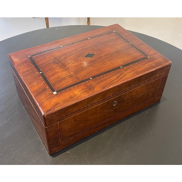 A beautifully crafted antique wooden keepsake box featuring richly figured wood and finely executed decorative inlay. The...