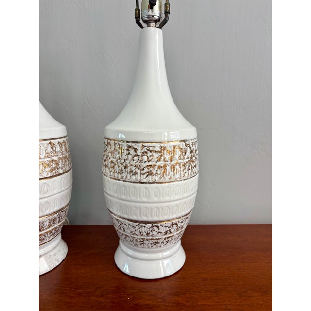 This refined pair of vintage mid-century modern table lamps features a crisp white ceramic glaze accented with original...
