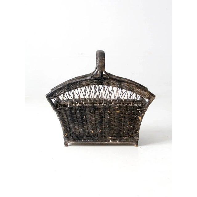 This is a vintage wicker magazine rack. The black wicker basket features two compartments with a top handle.