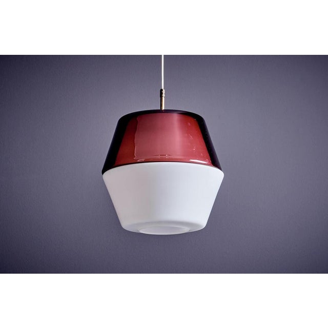 Pendant lamp with a brass frame and a two-piece glass shade, one of which is coloured. Made by Stilnovo in Italy around...