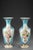 An enamel opaline baluster-shaped pair of vases decorated with polychromatic flowers in lobed cartridges on light blue...