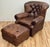 Vintage seasoned tufted leather Churchill wingback chair and matching ottoman by Restoration Hardware. Features iconic and...