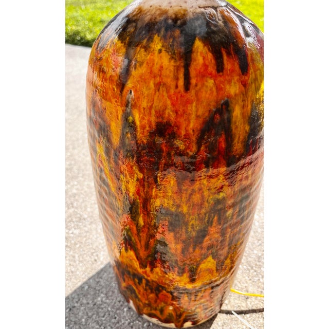 Brutalist Fat Lava table lamp with a two-tiered striped shade, c. 1970s. A vibrant orange drip glaze with brown and golden...