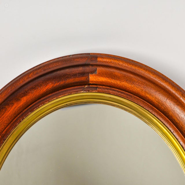 Incredible large antique oval mirror featuring a deep walnut frame with slightly different shades for each wood piece...