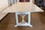 This generous rectangular dining table is finished in a beautifully distressed antique white, with warm wood tones peeking...