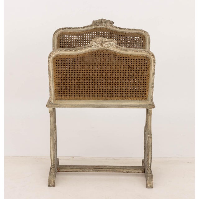 French Provincial Distressed Painted Carved Wood Cane Paneled Magazine Rack 34" H x 23" W x 13.75" D. Provenance: From a...