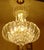 Featured is a six-tiered lucite chandelier with a gold-tone metal base. Measuring approximately 28 inches tall by 20...