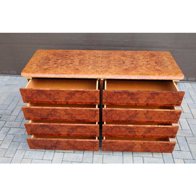 Rich burl wood veneer with dramatic swirling grain throughout the drawer fronts, top, and sides. Brass and black details....