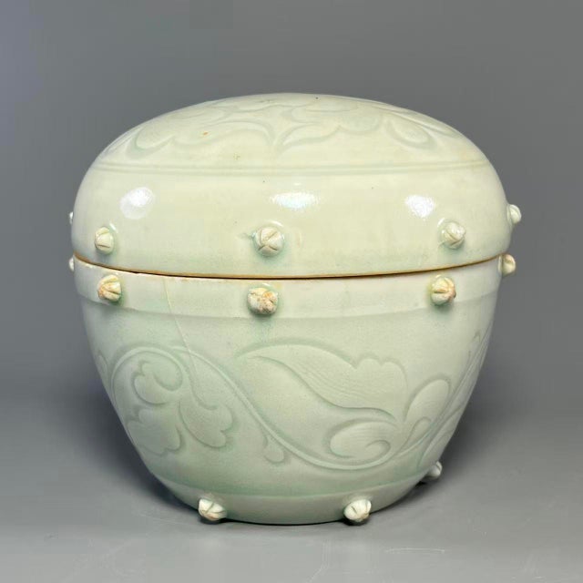 This lidded jar is crafted from authentic Longquan Celadon. It features soft celadon‑green glaze, relief‑carved floral...