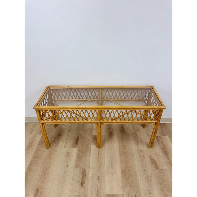 This vintage rattan console table showcases an intricate woven lattice pattern along its apron, offering the kind of hand-...