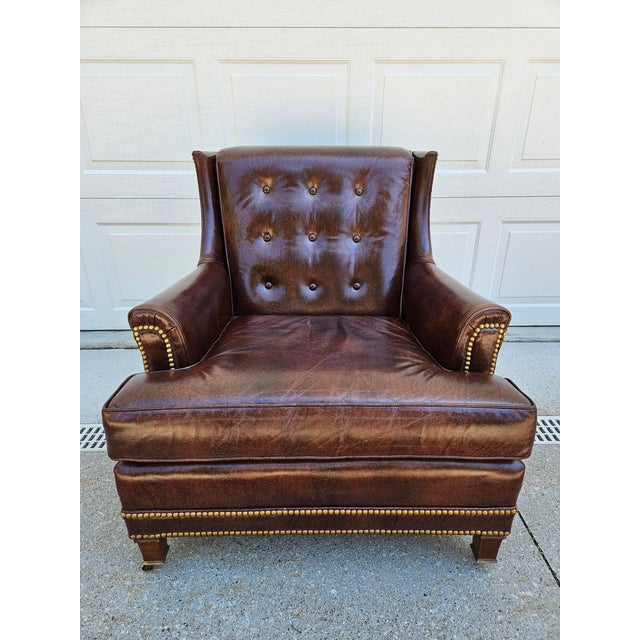 A vintage Hancock & Moore tufted lounge chair with brass tacks along the base and casters under the front legs. This...
