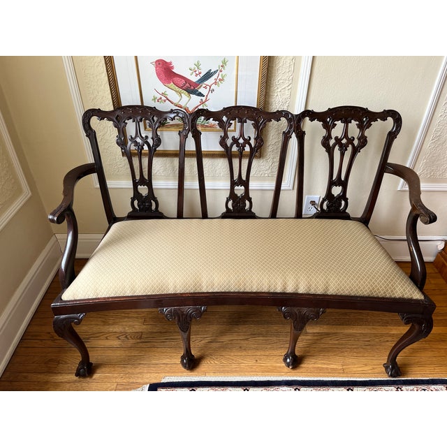 An unusual Chippendale style, triple chair settee of hand carved mahogany having a serpentine shaped top rail, 3...