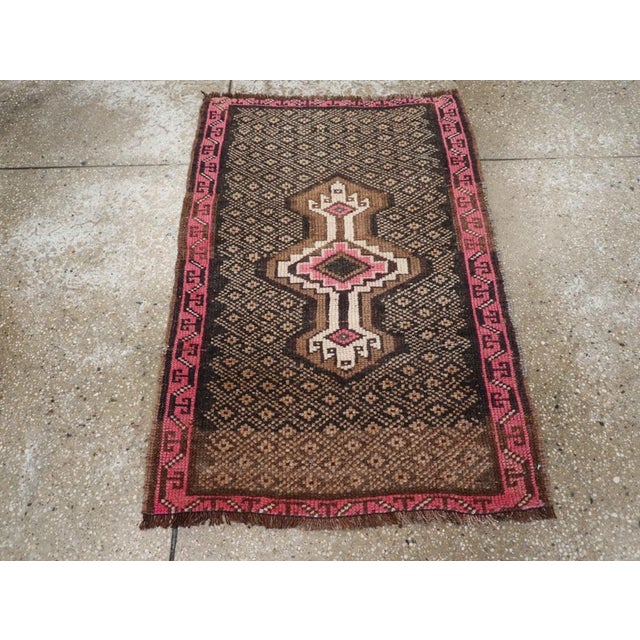 This mid-20th-century Turkish Anatolian throw rug presents a bold central composition set against a deep charcoal-brown...