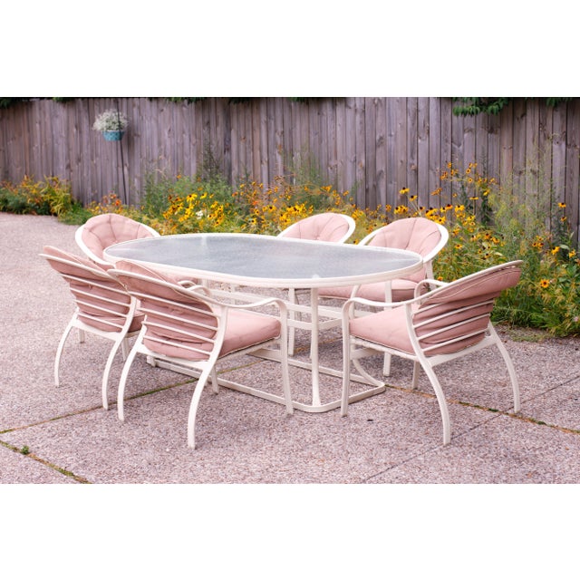 A timeless vintage outdoor dining set featuring six curved barrel-back Woodard chairs paired with a Tropitone Cantina oval...