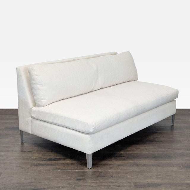 This CB2 loveseat features a clean and modern design with soft white upholstery and sturdy metal legs. Its compact size is...