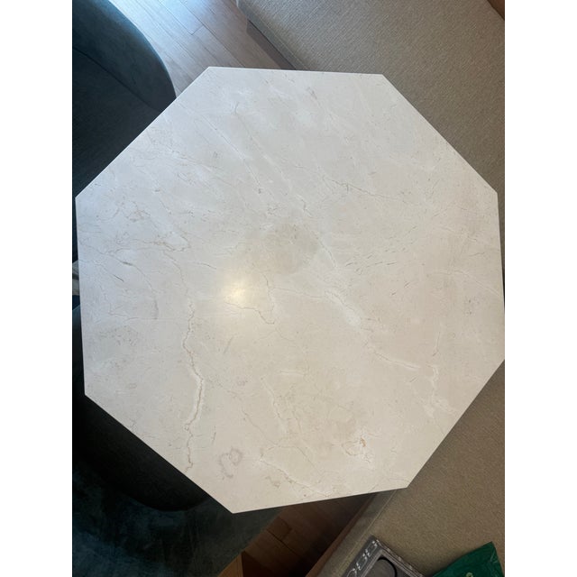 Cool marble round rests on an octagonal pedestal base of hand-applied reeded wood with shimmering antiqued gold finish....